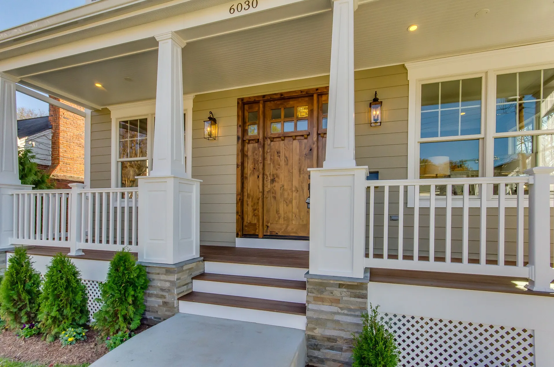 Finished front porch with columns, railings and new plantings