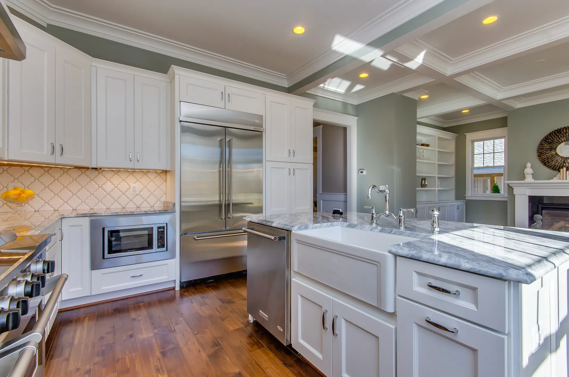 Remodeled kitchen with white cabinets, marble counters and a tile backsplash